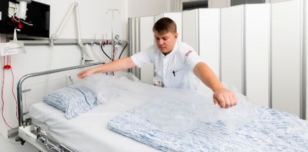 Mand lægger plastik over seng på sygehus